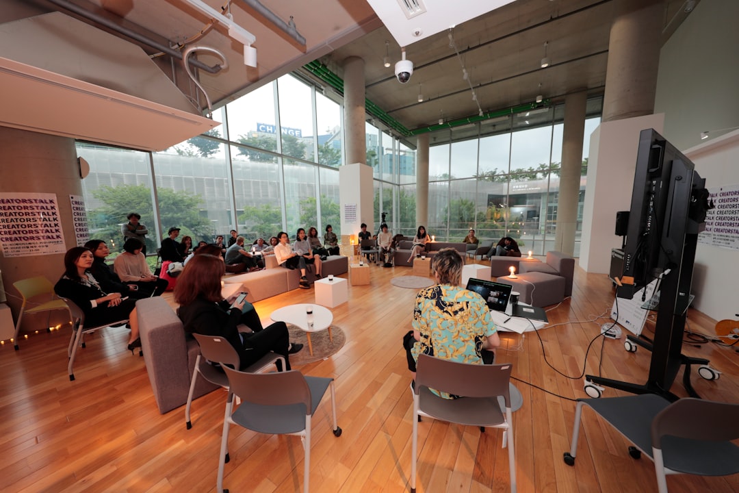 Photo by ASIA CULTURECENTER a group of people sitting in chairs in a room