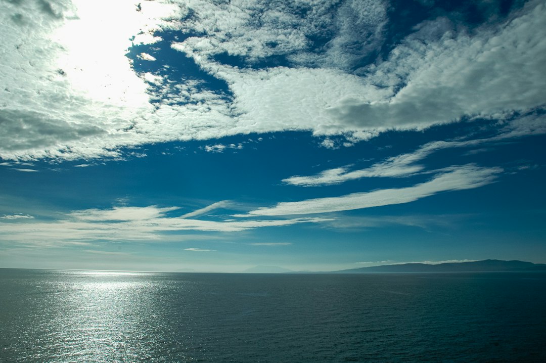 Photo by Rohit Tandon a view of a body of water with clouds in the sky